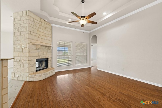 5620 Drystone Ln, Killeen, TX 76542 - unfurnished living room with a ceiling fan, arched walkways, crown molding, a raised ceiling, and a stone fireplace