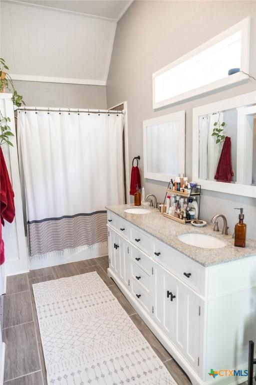 403 E 13th St, Shiner, TX 77984 - bathroom with double vanity, vaulted ceiling, and a shower with curtain