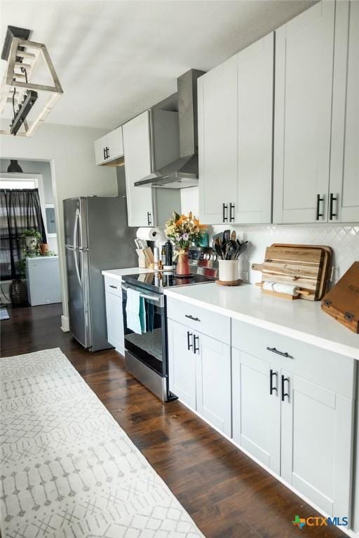 403 E 13th St, Shiner, TX 77984 - kitchen featuring stainless steel appliances, wall chimney range hood, light countertops, and dark wood-style floors