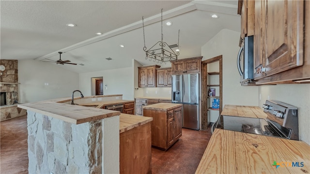 kitchen with a stone fireplace, stainless steel appliances, vaulted ceiling with beams, a center island, and sink