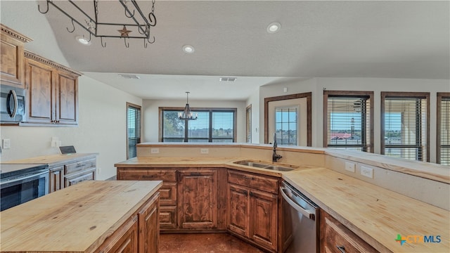 kitchen featuring an inviting chandelier, sink, butcher block countertops, pendant lighting, and appliances with stainless steel finishes