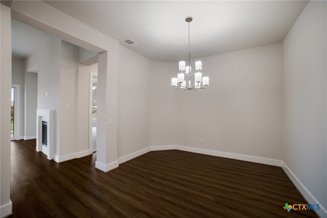 unfurnished room with a notable chandelier and dark hardwood / wood-style floors