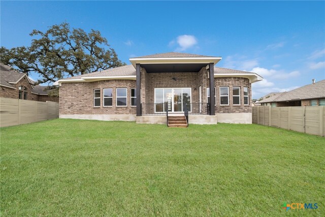 rear view of property with covered porch and a yard