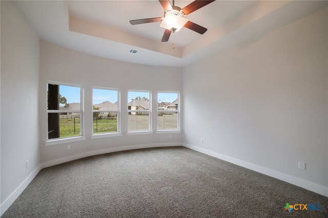 unfurnished room with a tray ceiling, carpet flooring, and ceiling fan