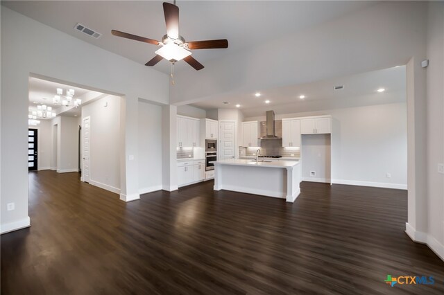 unfurnished living room with dark wood-type flooring, ceiling fan with notable chandelier, and sink