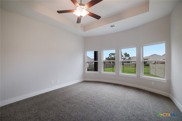 carpeted spare room featuring ceiling fan and a tray ceiling