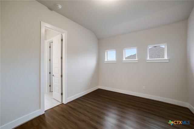 unfurnished room featuring dark hardwood / wood-style flooring and lofted ceiling