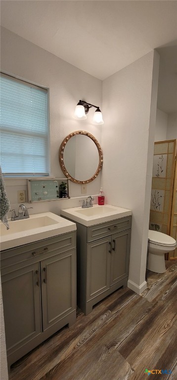 502 S 9th St, Seadrift, TX 77983 - full bathroom featuring toilet, wood finished floors, two vanities, and a sink
