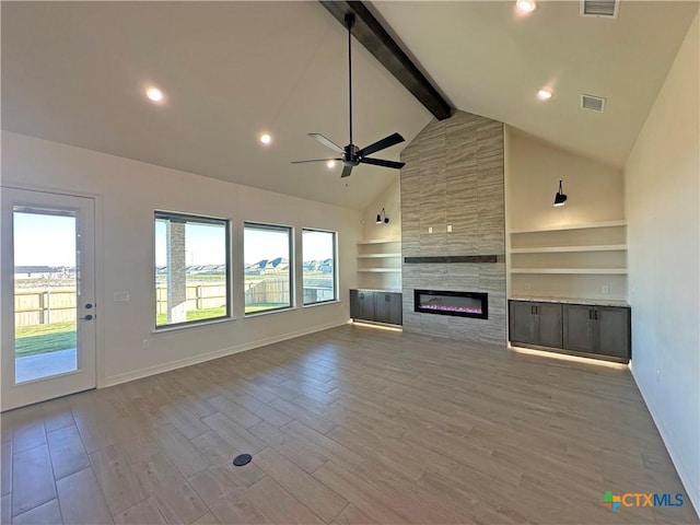 unfurnished living room featuring a tile fireplace, ceiling fan, high vaulted ceiling, beam ceiling, and built in features