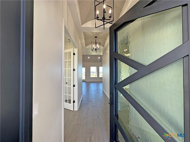 corridor with french doors, an inviting chandelier, and hardwood / wood-style flooring