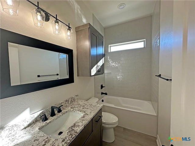 full bathroom featuring toilet, hardwood / wood-style flooring, tiled shower / bath, and vanity