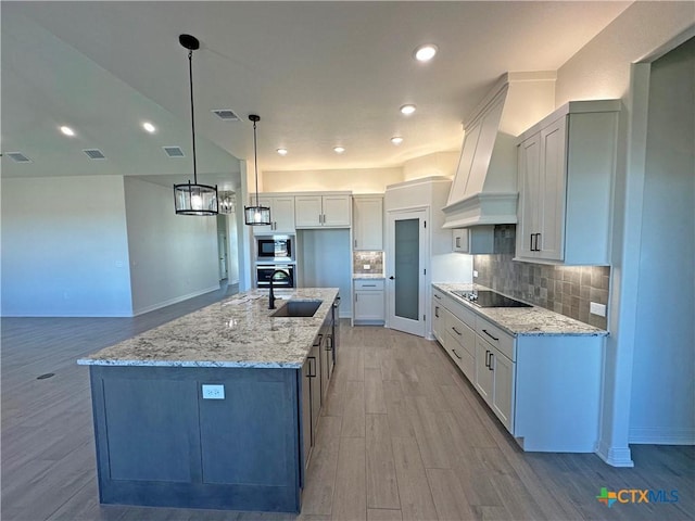 kitchen with decorative light fixtures, a large island, white cabinetry, and custom exhaust hood