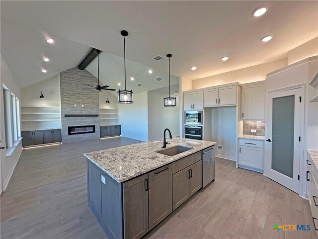 kitchen featuring stainless steel appliances, a center island with sink, white cabinetry, ceiling fan, and sink