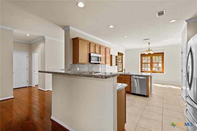 kitchen featuring ornamental molding, kitchen peninsula, stainless steel appliances, and light hardwood / wood-style floors