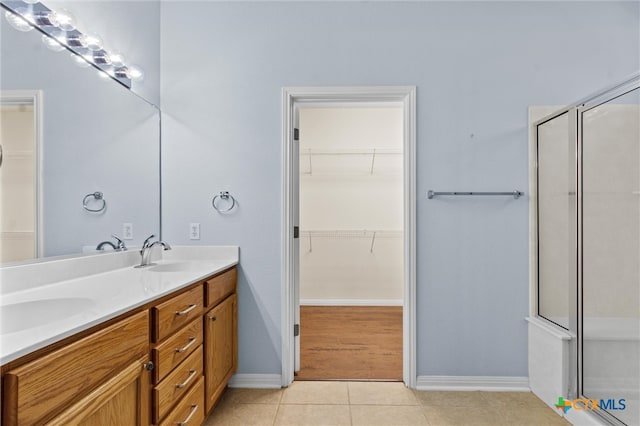 bathroom with walk in shower, vanity, and tile patterned floors