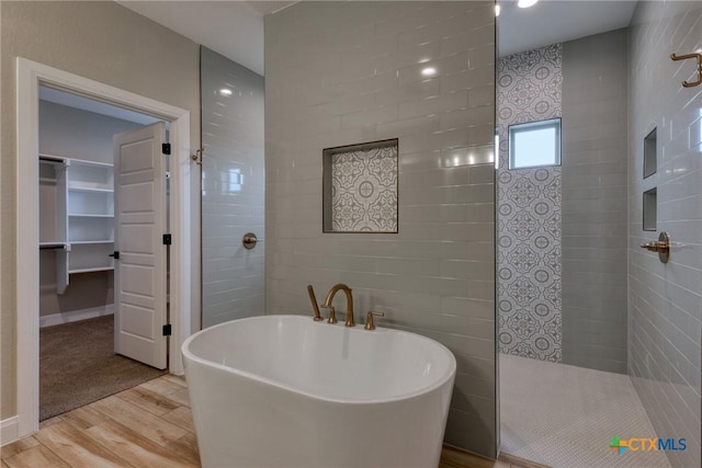109 Wild Persimmon Trl, Marion, TX 78124 - bathroom featuring wood finished floors, a freestanding tub, walk in shower, and a spacious closet