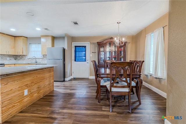 dining space featuring sink, dark wood-type flooring, and a chandelier