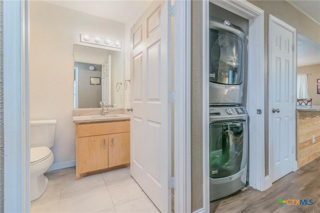 laundry area featuring light tile patterned flooring, sink, and stacked washer and clothes dryer