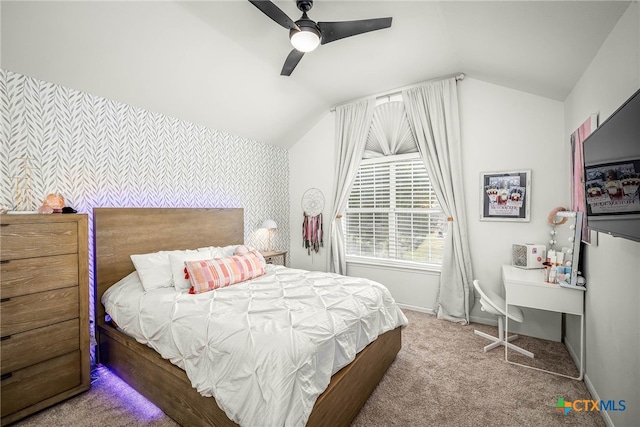 carpeted bedroom featuring lofted ceiling, wallpapered walls, baseboards, ceiling fan, and an accent wall