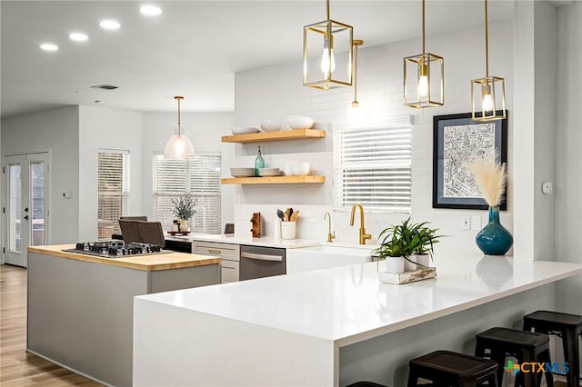 kitchen with a breakfast bar, light wood-style flooring, appliances with stainless steel finishes, wood counters, and a sink