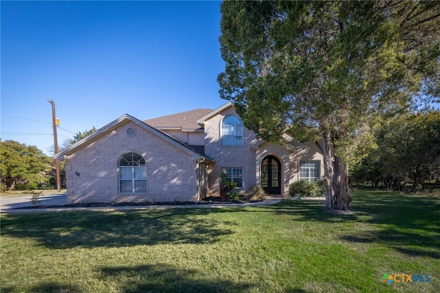 traditional-style home with brick siding, french doors, and a front lawn