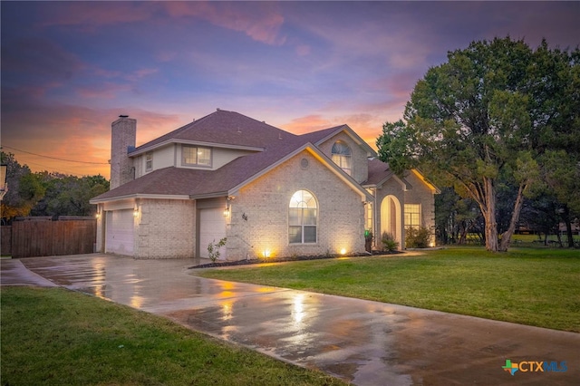 view of front of house with driveway, a yard, a chimney, a garage, and brick siding