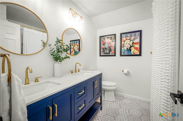 bathroom with double vanity, toilet, lofted ceiling, and a sink