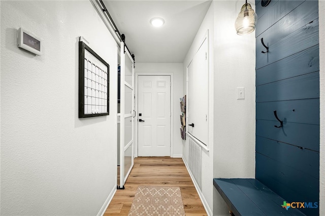 entryway with a barn door, baseboards, and light wood finished floors