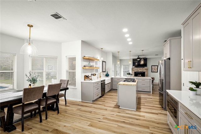 kitchen with visible vents, gray cabinets, stainless steel appliances, light countertops, and light wood-type flooring