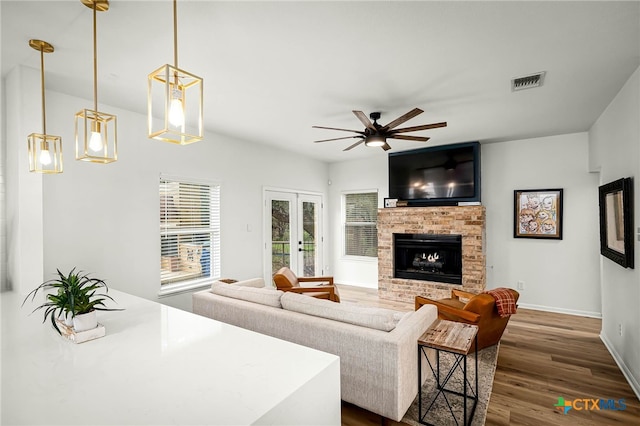 living room with a ceiling fan, dark wood-style floors, visible vents, baseboards, and a brick fireplace