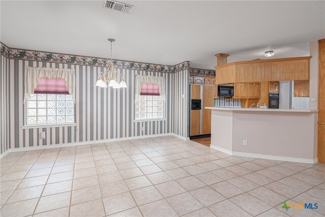 kitchen featuring kitchen peninsula, plenty of natural light, black appliances, and a notable chandelier