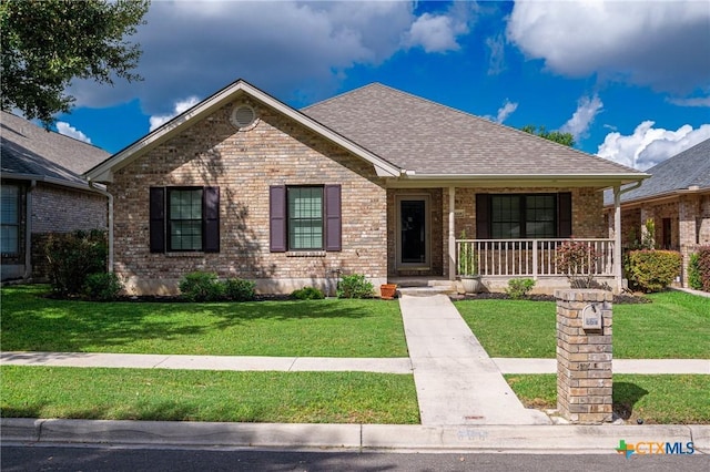 view of front of property with a porch, brick siding, a shingled roof, and a front lawn