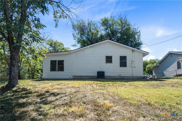 back of property with cooling unit and a yard