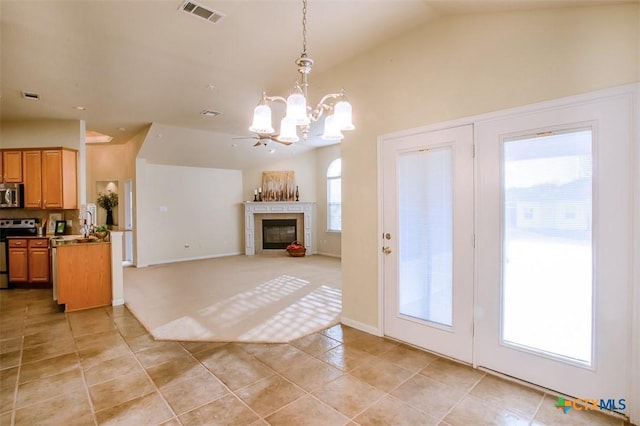 interior space with lofted ceiling, an inviting chandelier, visible vents, and a glass covered fireplace