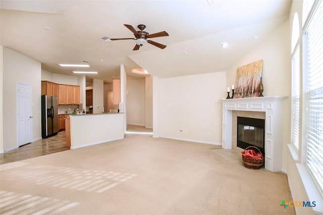 unfurnished living room featuring a ceiling fan, a tile fireplace, light carpet, and baseboards