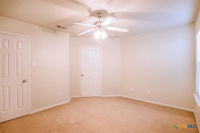 spare room featuring a ceiling fan, visible vents, light carpet, and baseboards