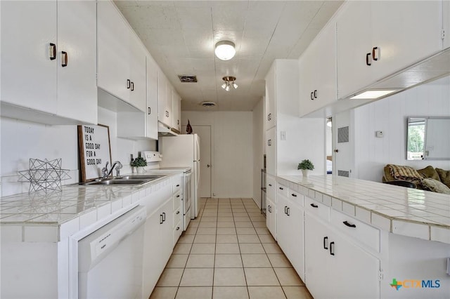 284 Lake Frst, Canyon Lake, TX 78133 - kitchen featuring white dishwasher, stove, light tile patterned floors, a peninsula, and white cabinets