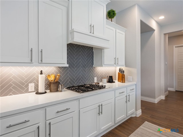 kitchen with custom exhaust hood, stainless steel gas stovetop, backsplash, dark wood-type flooring, and white cabinets