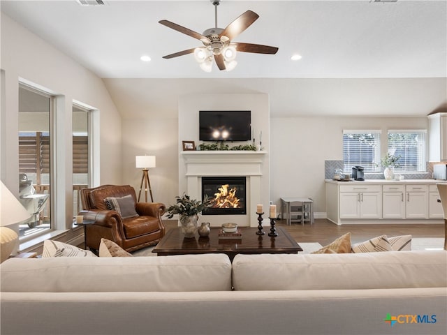 living room featuring lofted ceiling, ceiling fan, and light wood-type flooring