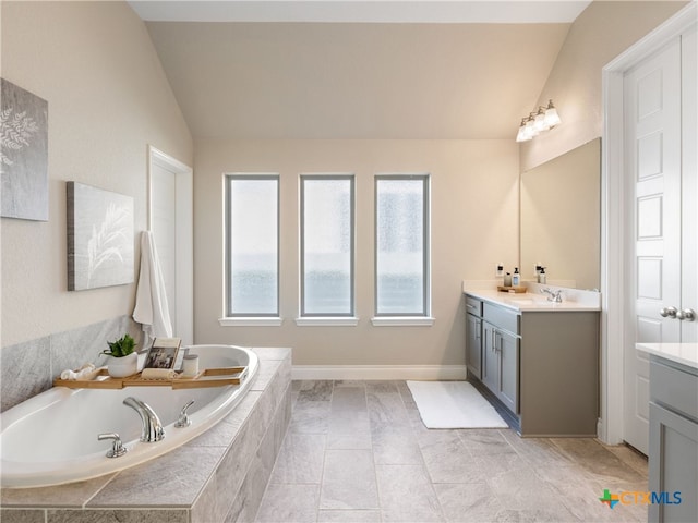 bathroom with vanity, lofted ceiling, and tiled bath