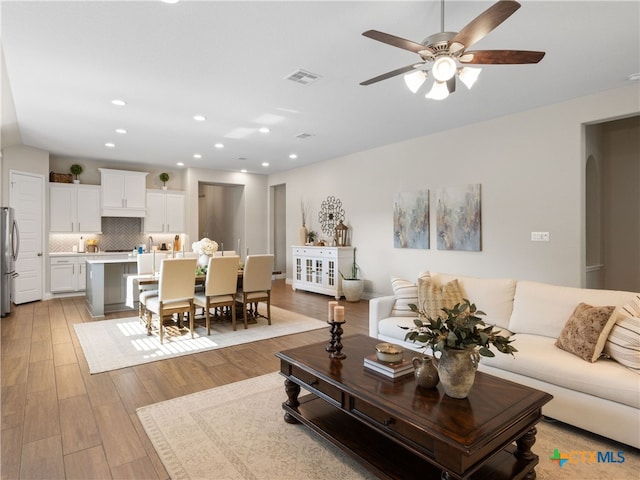 living room with ceiling fan and light hardwood / wood-style floors