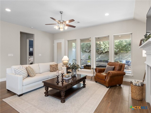 living room featuring hardwood / wood-style flooring, ceiling fan, and vaulted ceiling