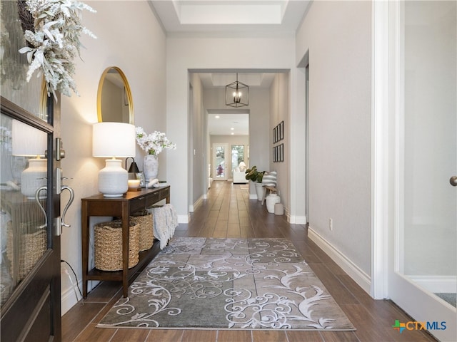 hall with dark wood-type flooring and a chandelier