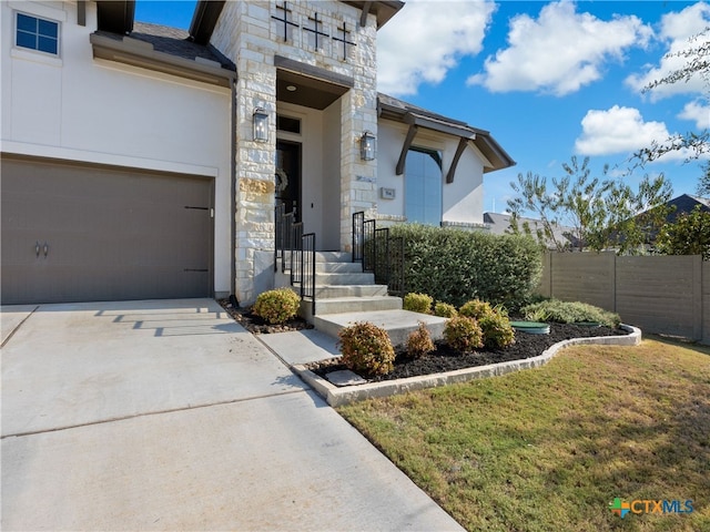 entrance to property with a garage and a lawn