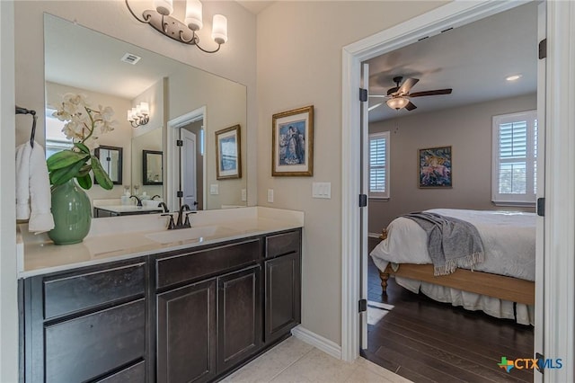 ensuite bathroom with ensuite bathroom, wood finished floors, vanity, visible vents, and baseboards