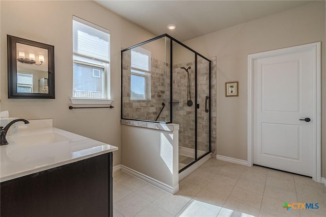 bathroom featuring tile patterned floors, a stall shower, a sink, and baseboards