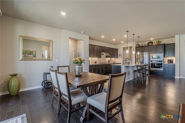 dining room with dark wood-type flooring, recessed lighting, and baseboards