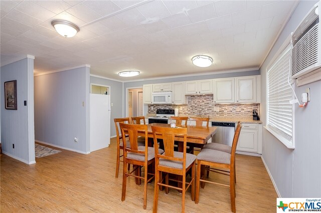 dining room with a wall unit AC, light wood-style floors, baseboards, and ornamental molding