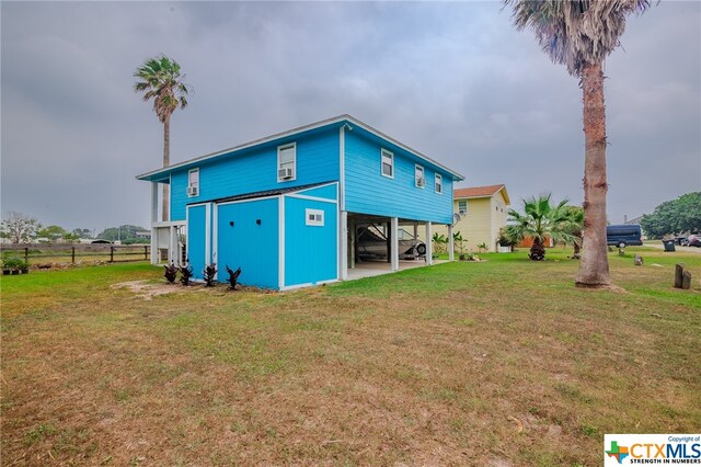 back of property featuring a carport, a lawn, and fence