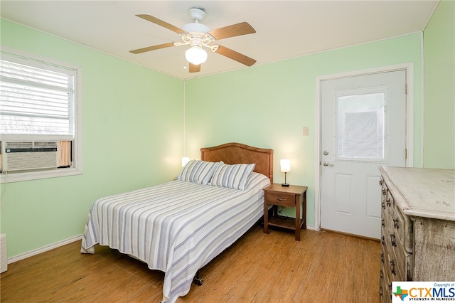 bedroom with light wood finished floors, cooling unit, a ceiling fan, and baseboards